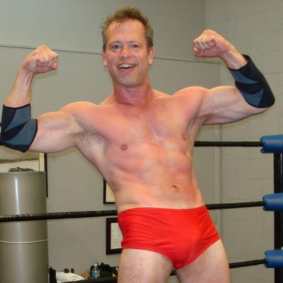 muscle jock wrestler posing in pro wrestling ring at pro show