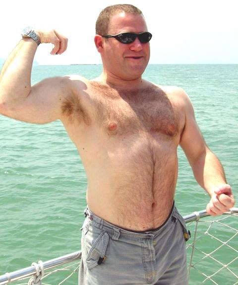 very hairy daddy bear flexing big muscles on boat